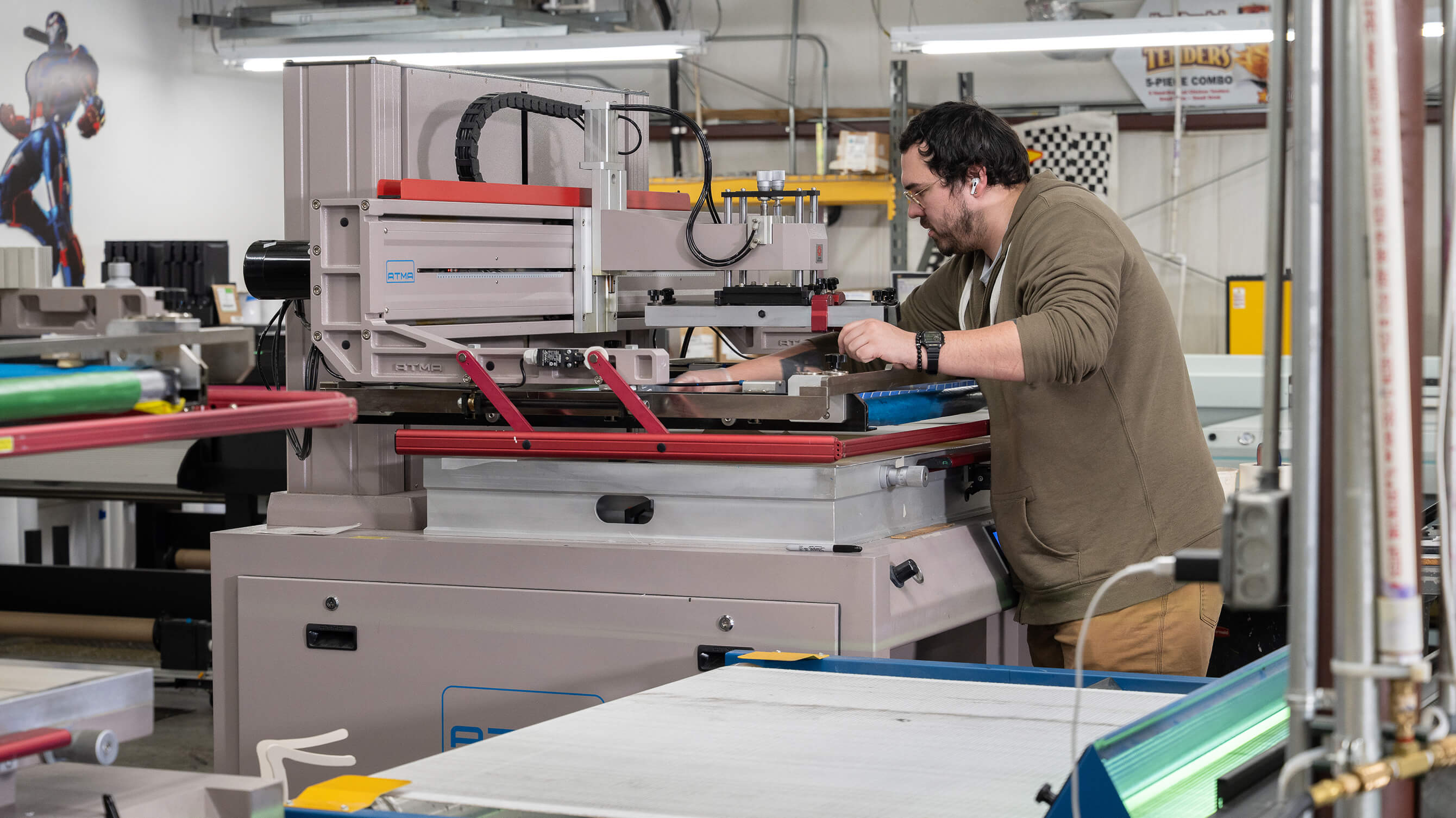 A technician running an ATMA screen-printing press