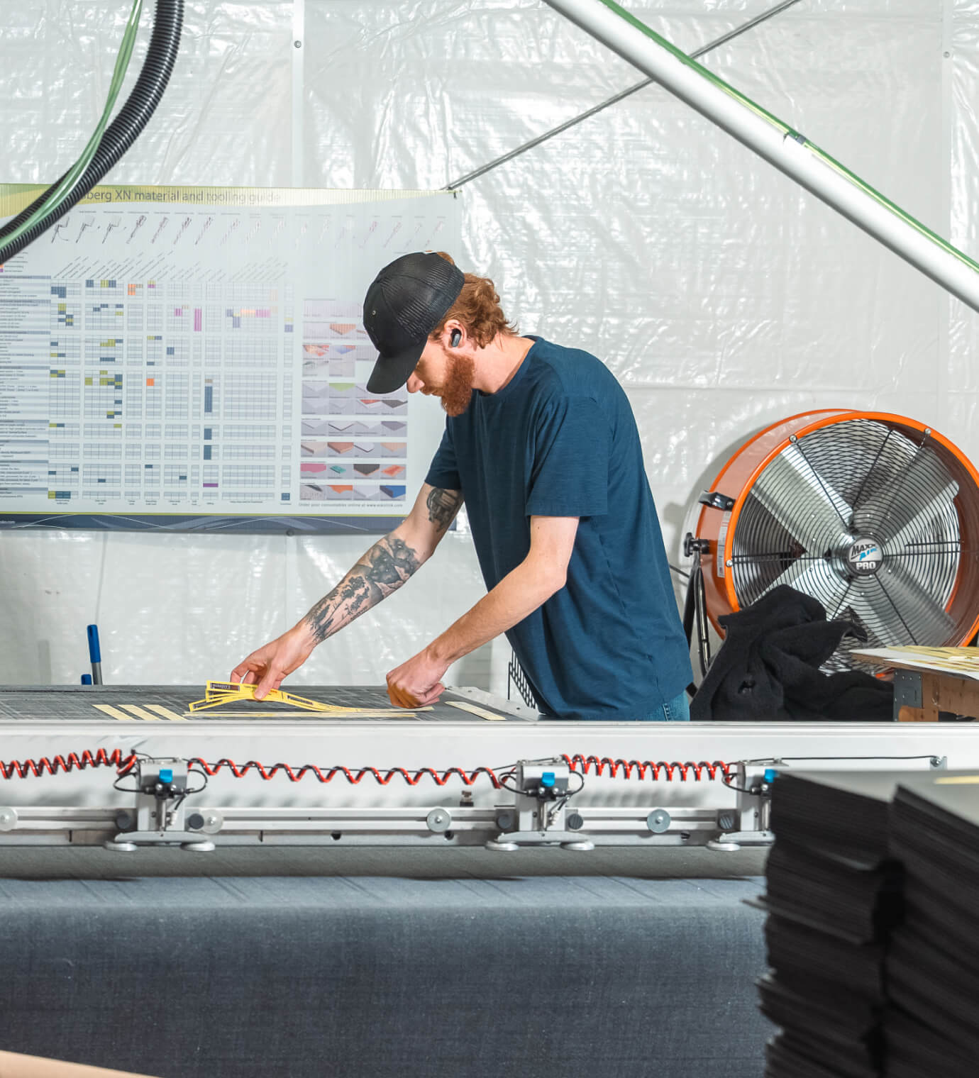 A worker weeding yellow knife-cut labels at a flatbed cutting table