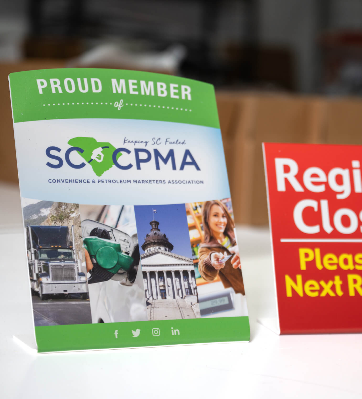 A flatbed-printed SCPMA proud-member table sign beside a red Register Closed sign