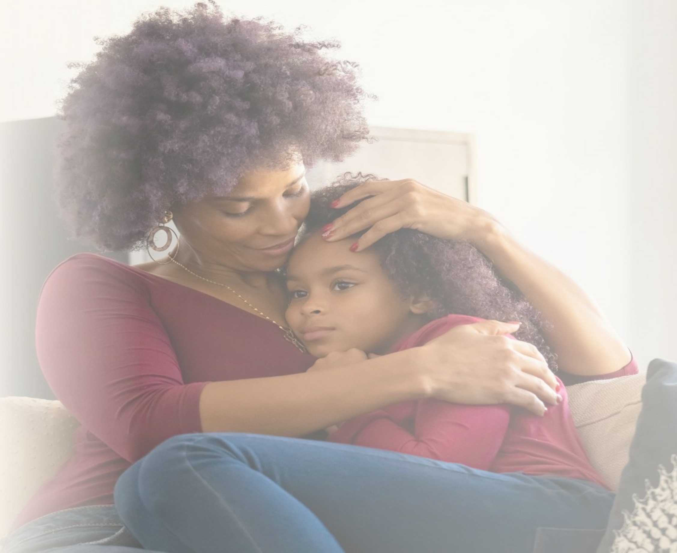 A parent holding their child close on a couch