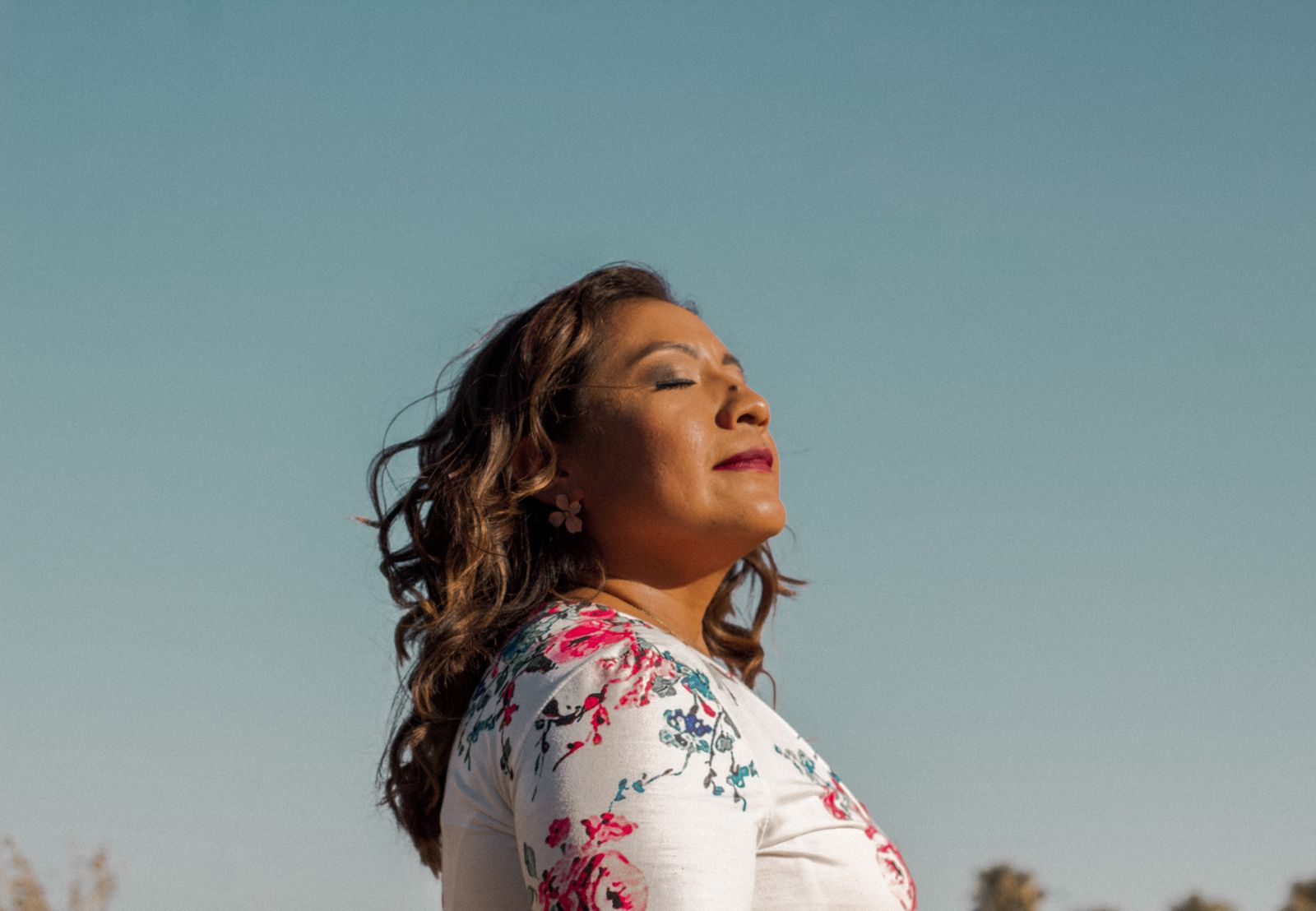 Woman outdoors with her eyes closed, breathing calmly in the sunshine