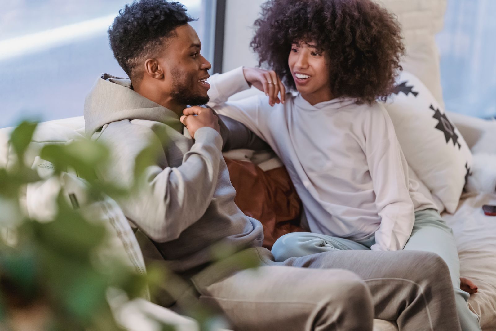 A couple sitting together on a couch at home, smiling and talking