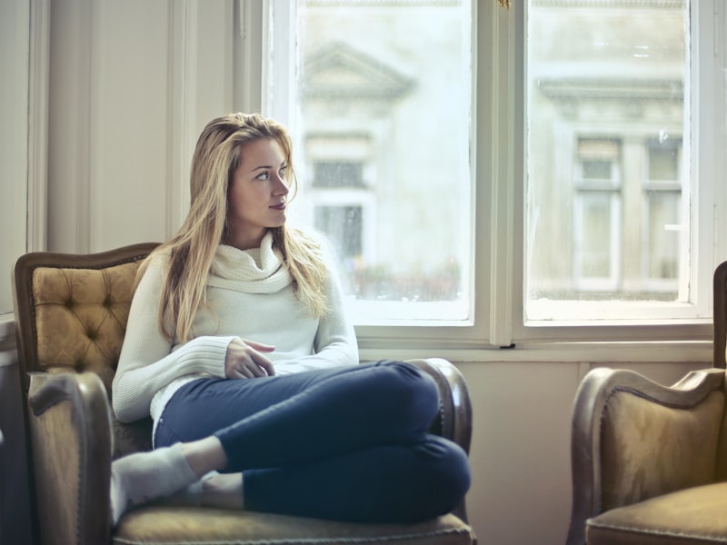 A woman sitting alone in an armchair by a window