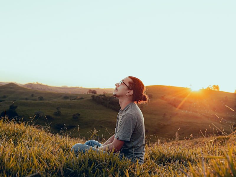 A man sitting outdoors at sunset with his face turned toward the light