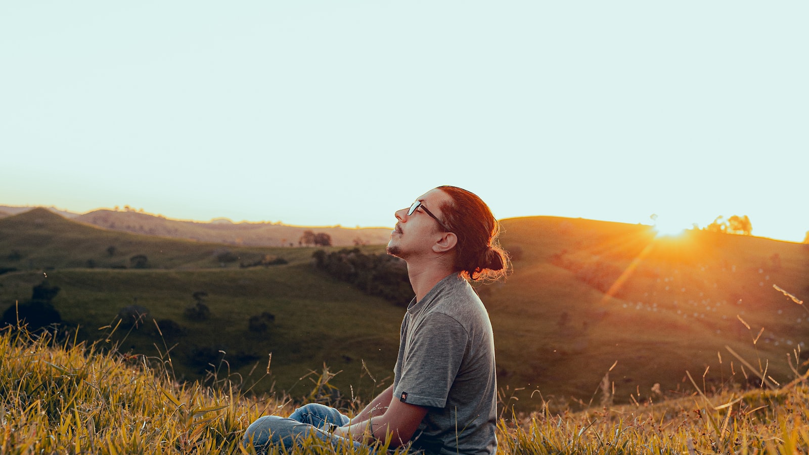 A man sitting outdoors at sunset with his face turned toward the light
