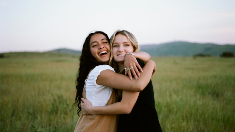 Two people embracing in a field at golden hour