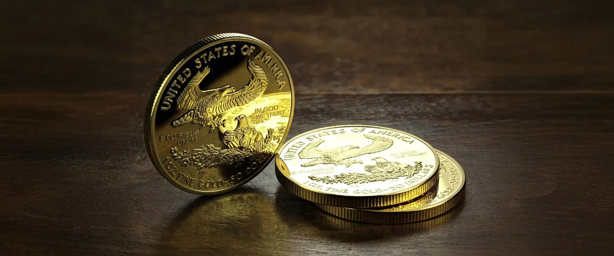 Stack of American Gold Eagle coins on a wooden surface — United States of America 1 oz fine gold $50 coins