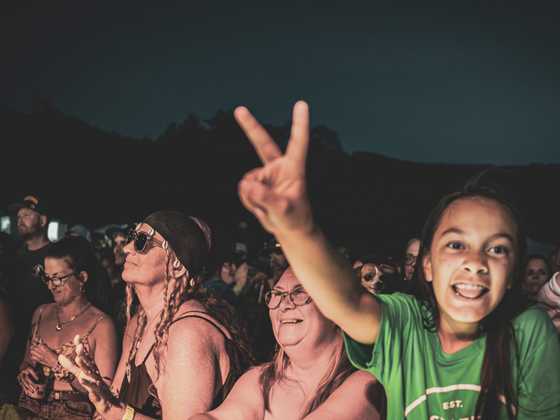 Young fan smiling and flashing a peace sign in the crowd at a night show