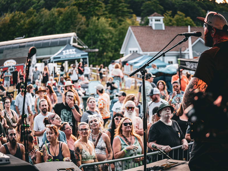 View from the stage of a guitarist playing to a smiling crowd