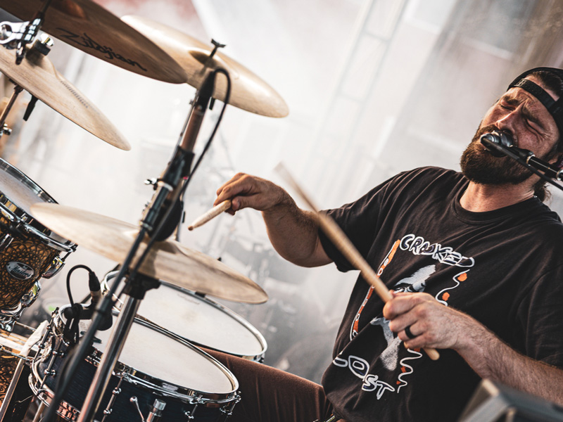 Drummer singing into a microphone mid-performance