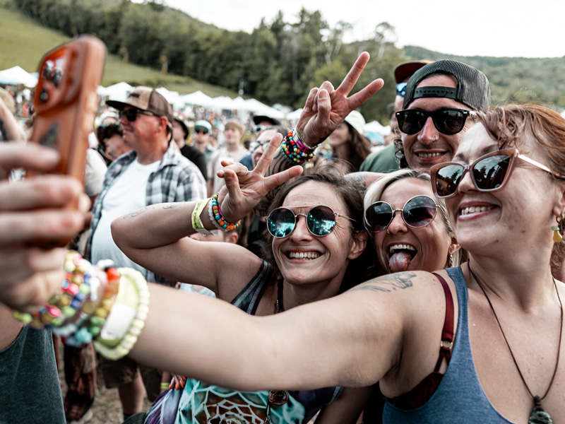Friends taking a selfie and flashing peace signs in the festival crowd