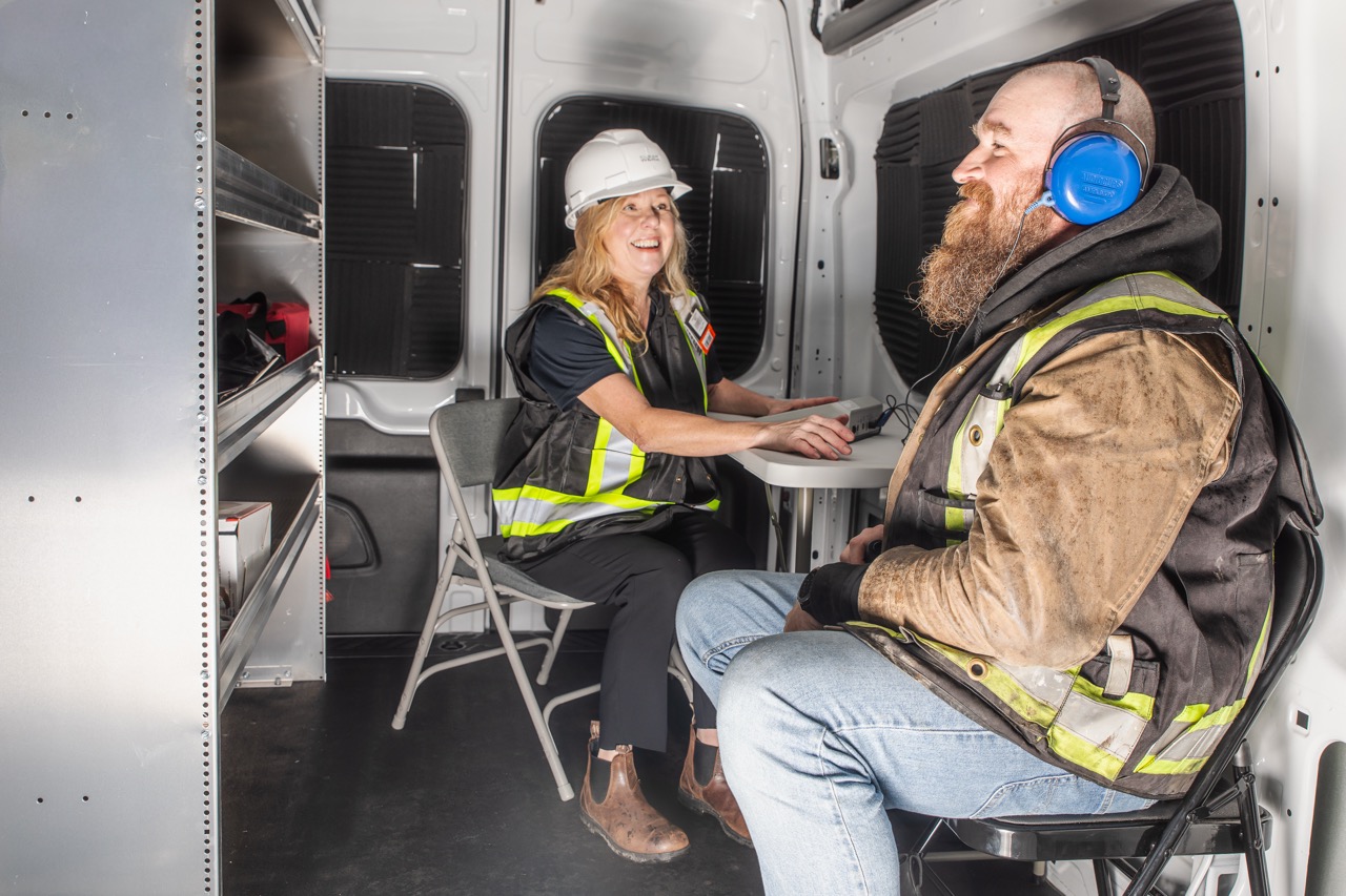 Clear Work technician running a hearing test for a construction worker inside the mobile testing van