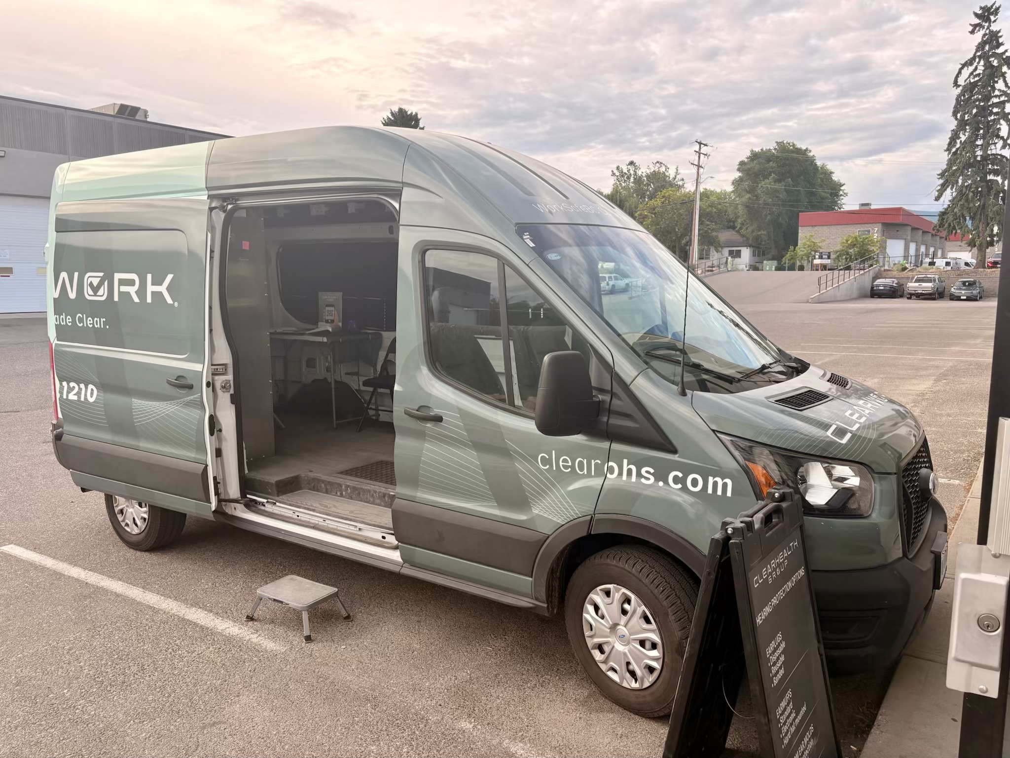 The Clear Work mobile hearing testing unit parked with its side door open and step stool down, showing the fitted interior where testing takes place