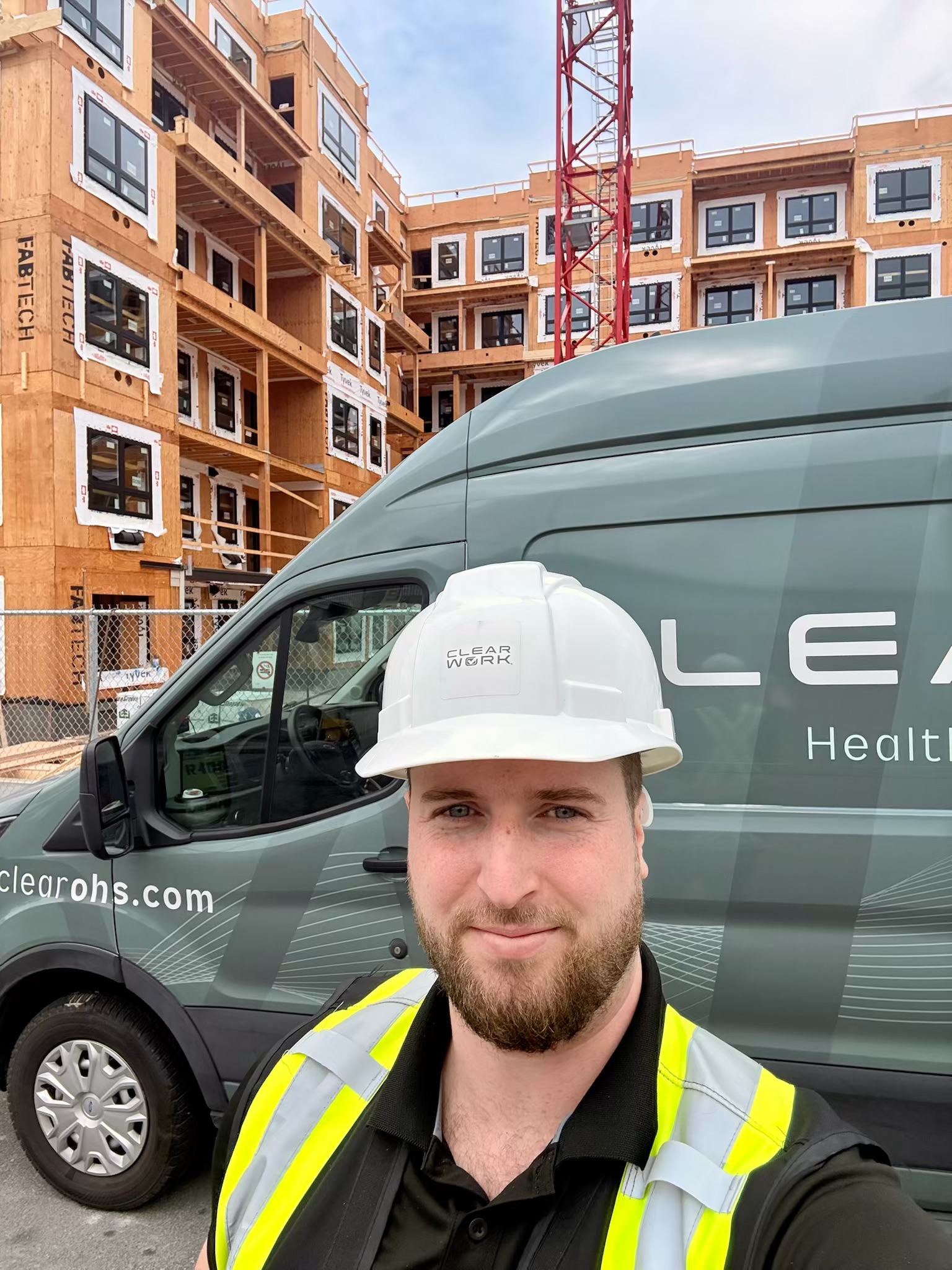 Clear Work technician in a hard hat beside one of our mobile hearing testing units at a Langley construction site