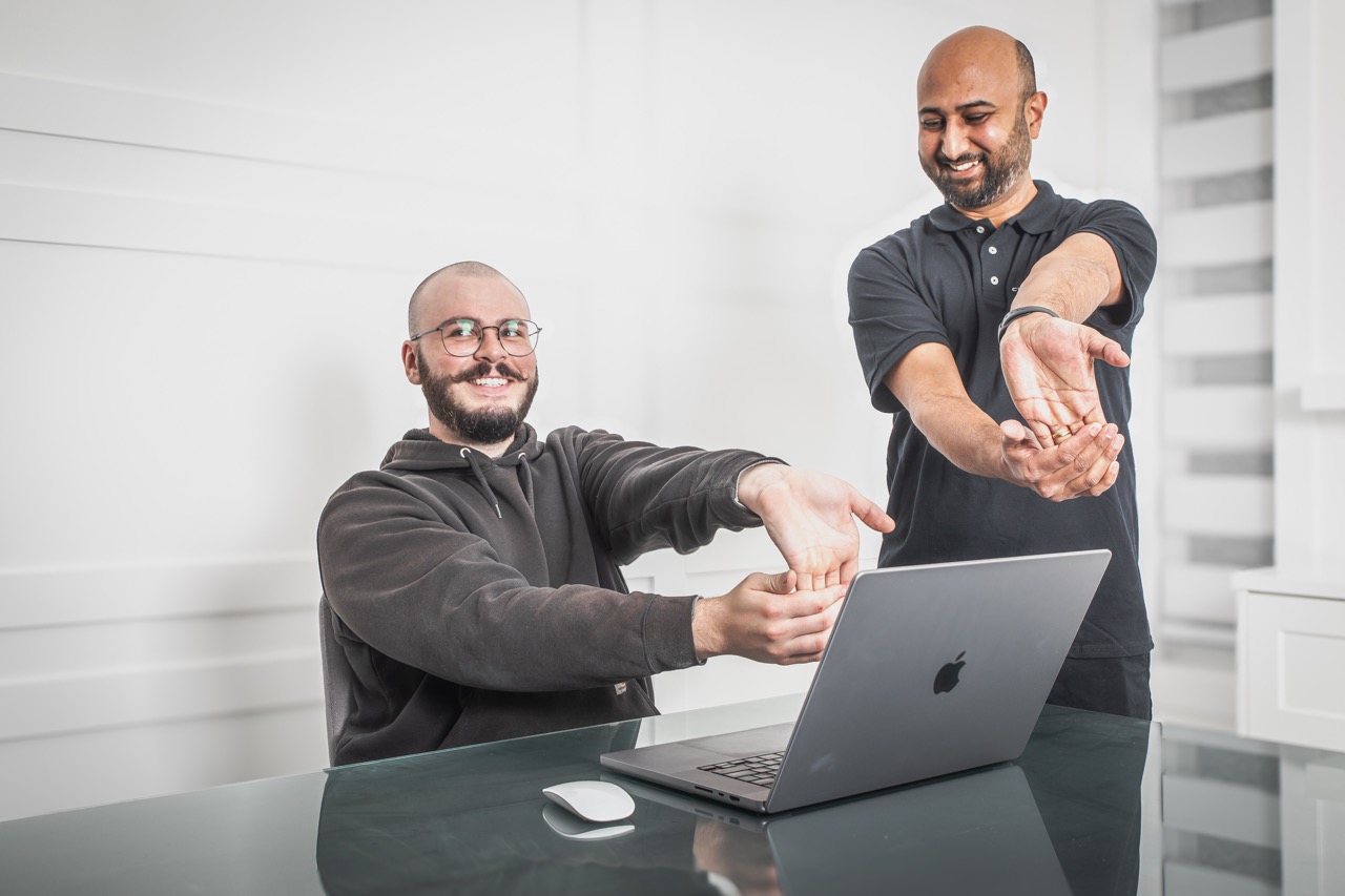 Worker and ergonomic assessor going through stretches at the workstation