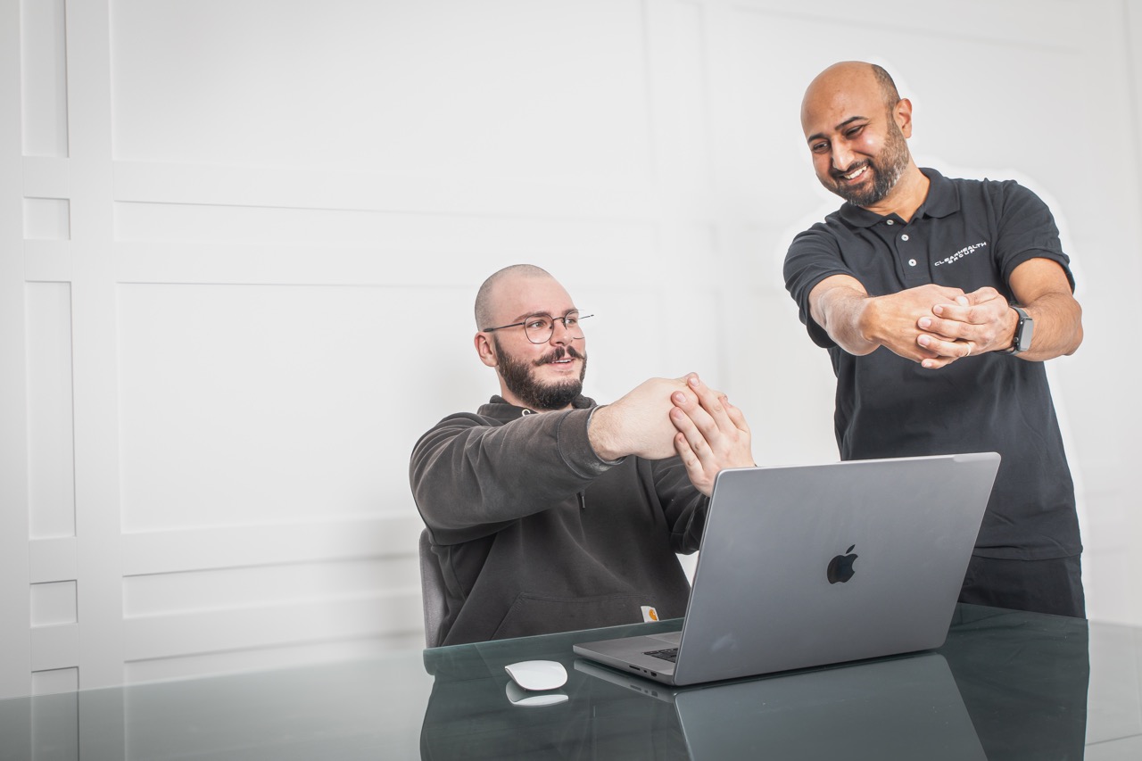 Ergonomic assessor showing a seated worker a hand and finger stretch at their desk
