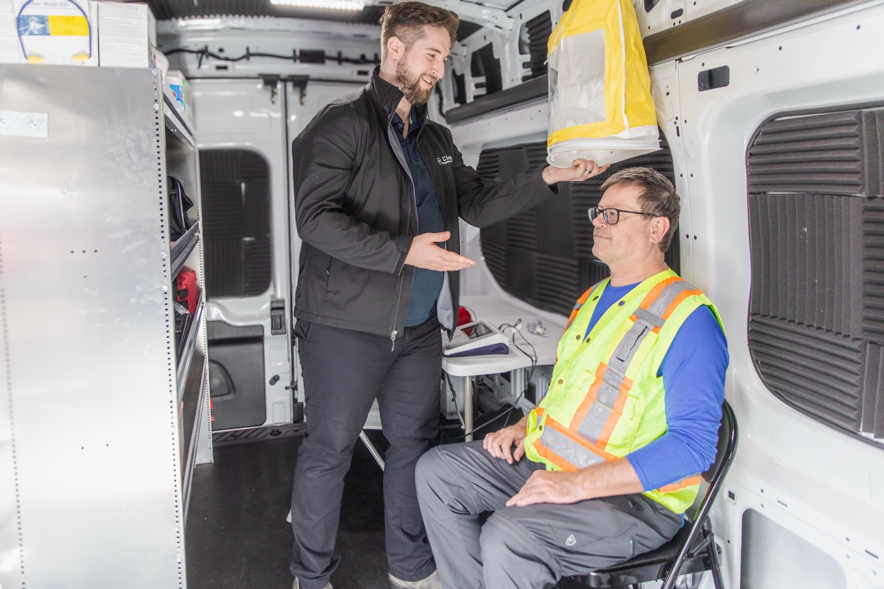 Fitting the test hood over a seated worker before a respirator fit test