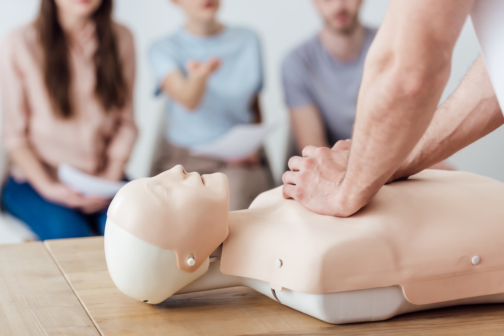 Chest compressions being practised on a CPR manikin during a first aid class