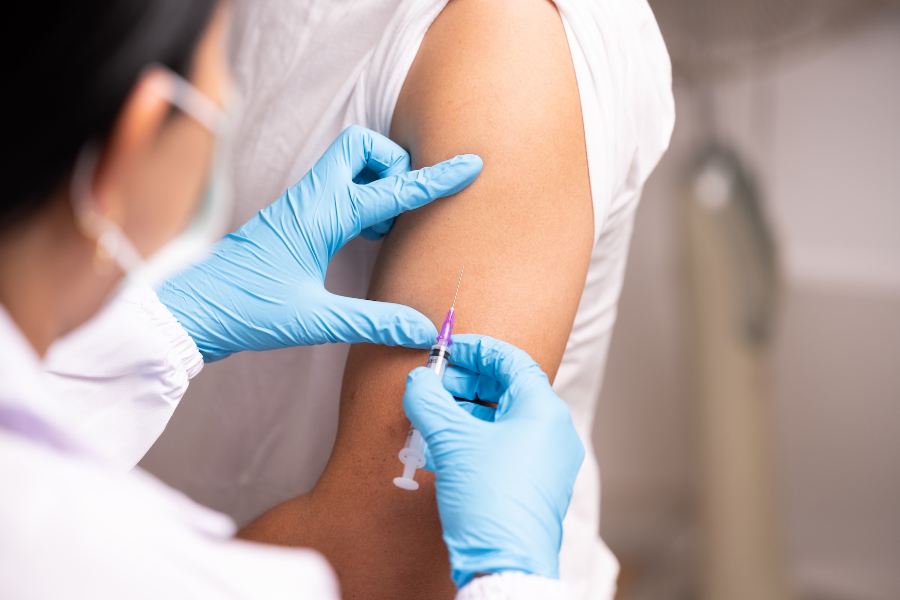 Registered nurse giving a flu vaccination into a worker's upper arm