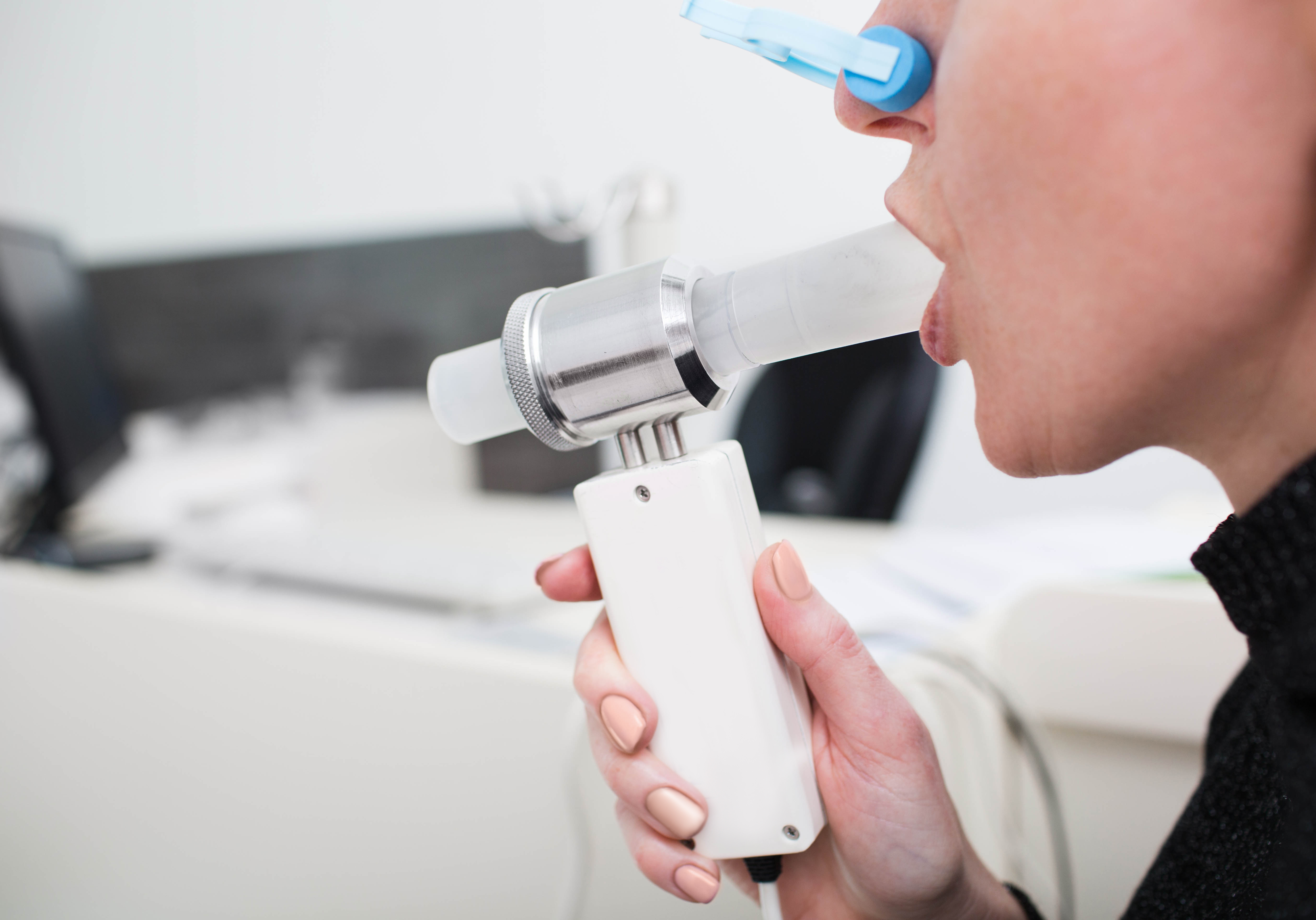 Worker breathing into a spirometer mouthpiece during a lung function test