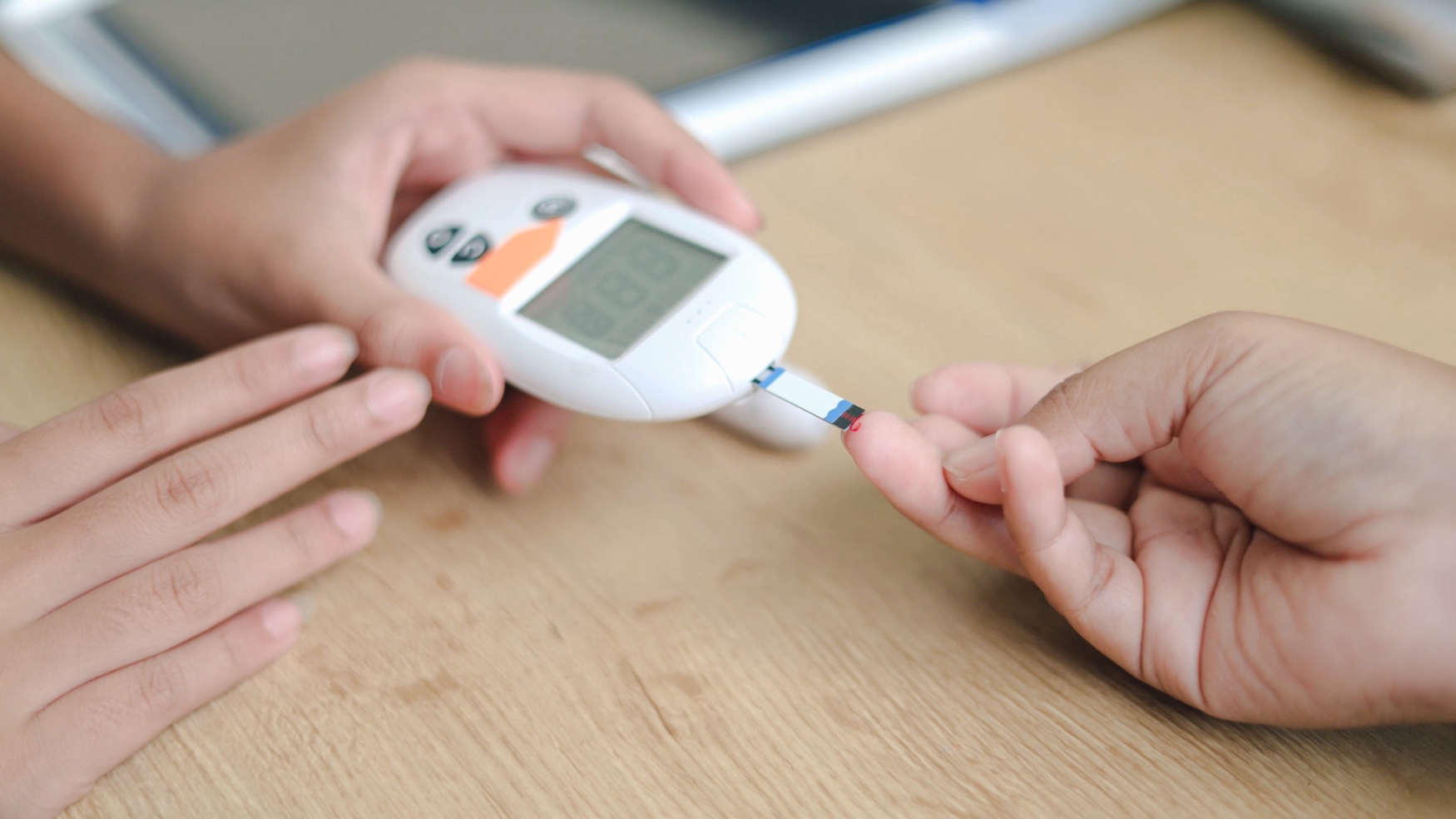 Blood glucose reading being taken from a fingertip with a glucose meter