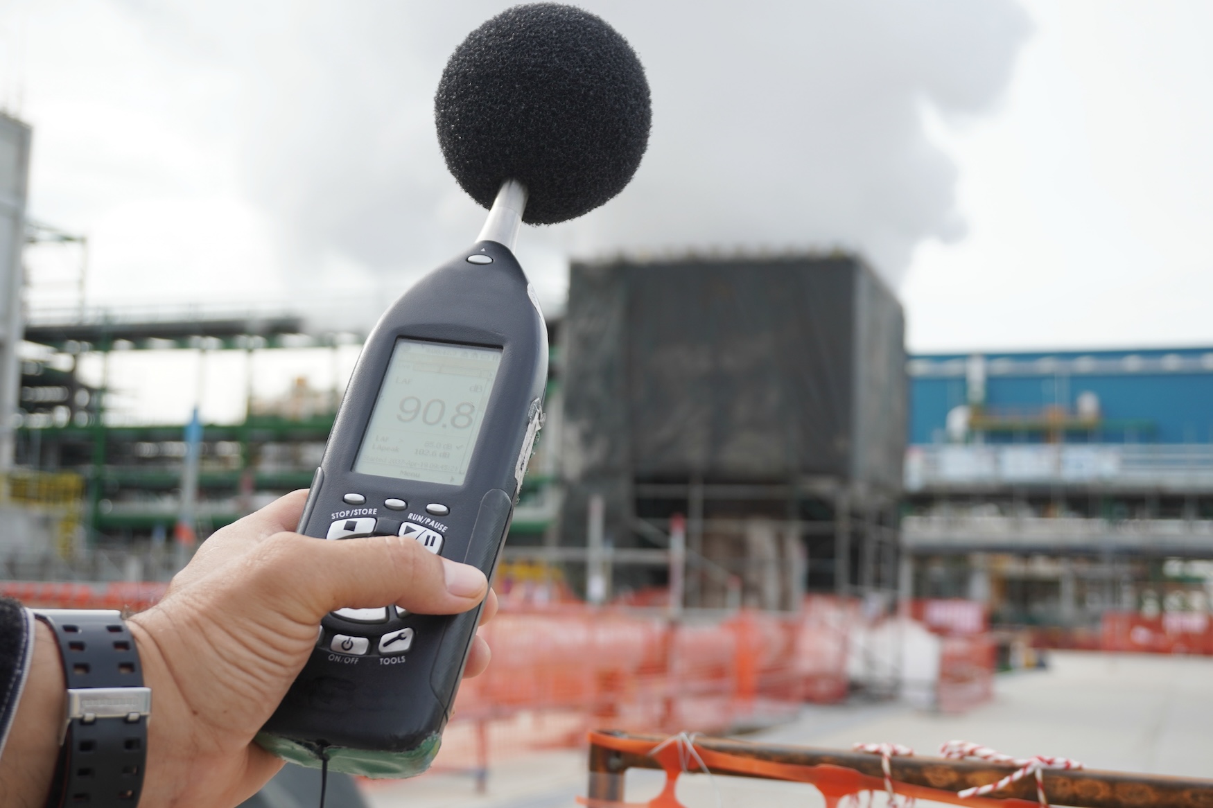 Sound level meter being used to take a noise reading at an industrial site