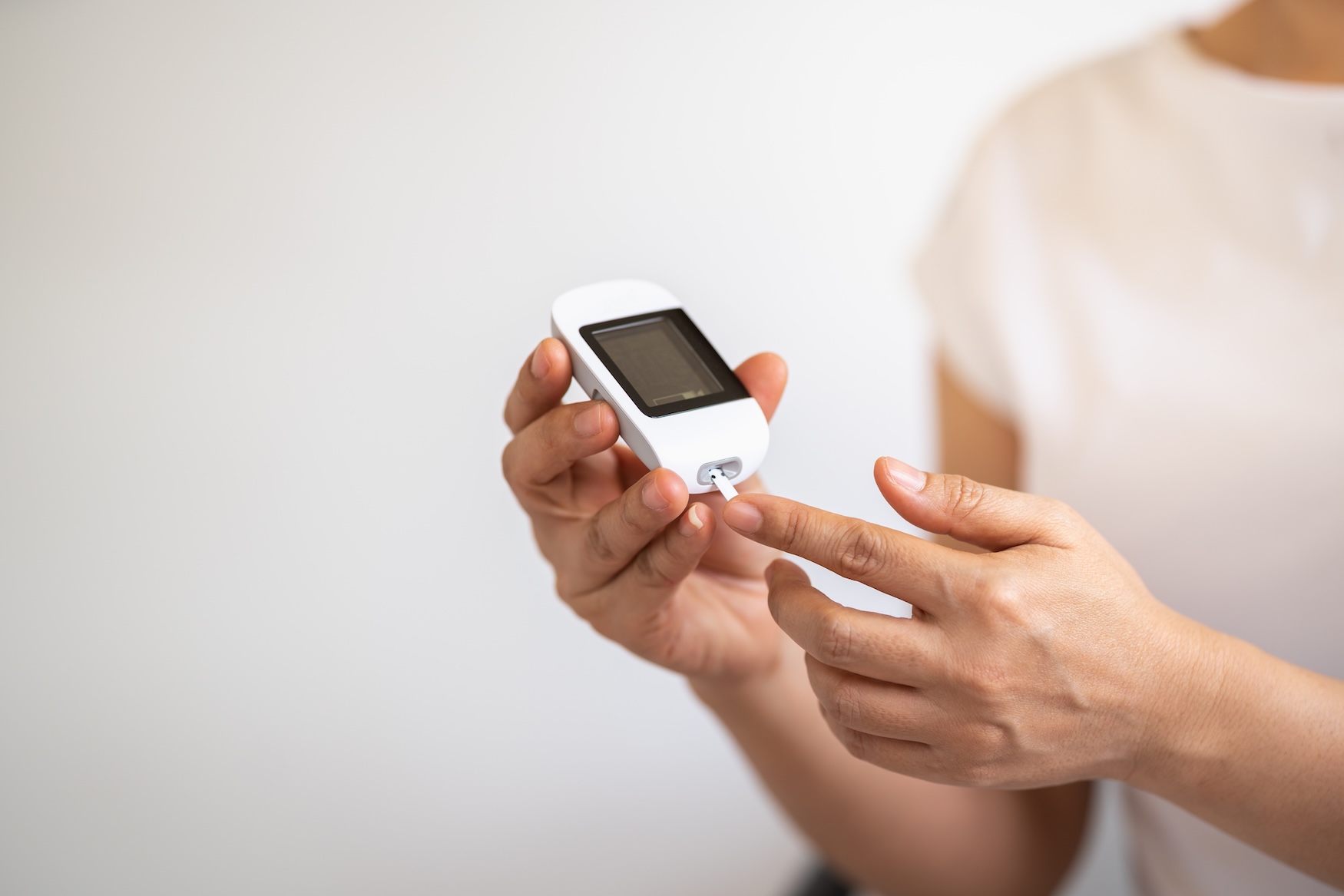 Hands using a glucose meter to check blood sugar during a health screening