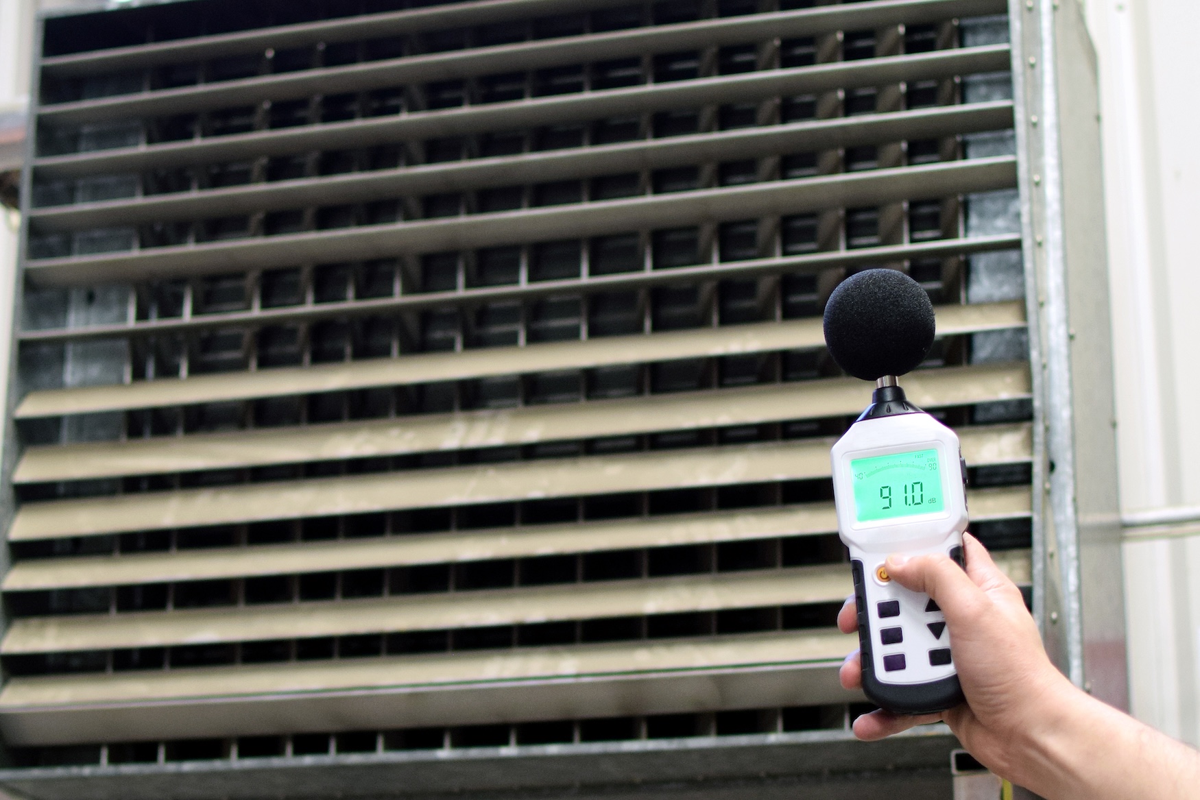 Sound level meter reading 91 decibels beside industrial ventilation plant