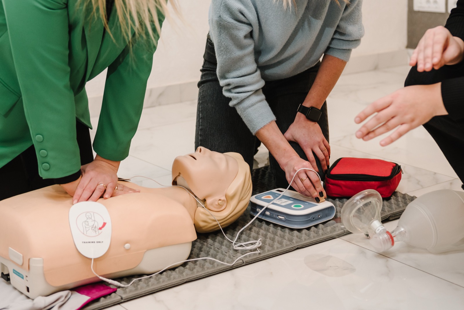 AED trainer and CPR manikin in use during a first aid training session