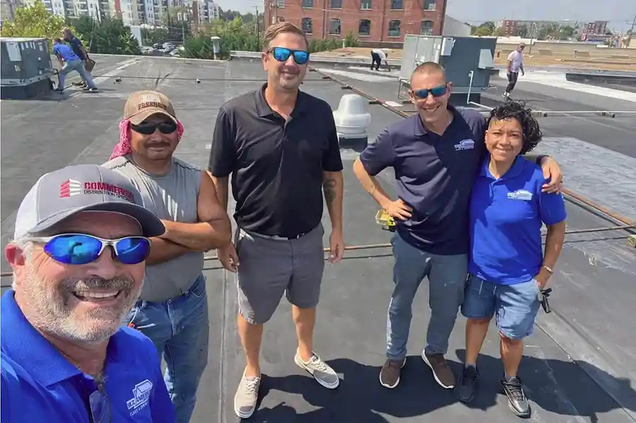 Owner May Anderson overseeing a roofing project in Virginia Beach, verifying VCC code compliance.