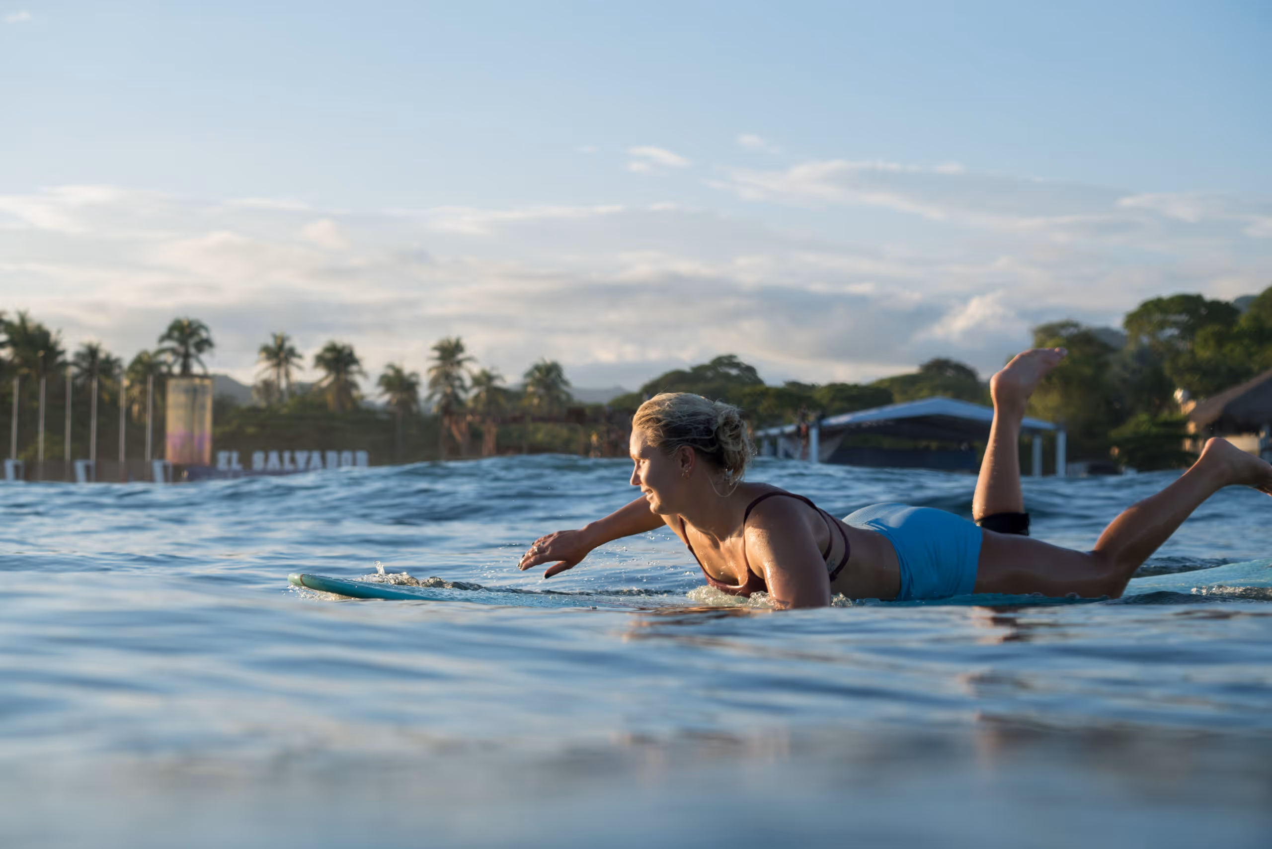 A surfer paddling out at sunrise in El Zonte, El Salvador