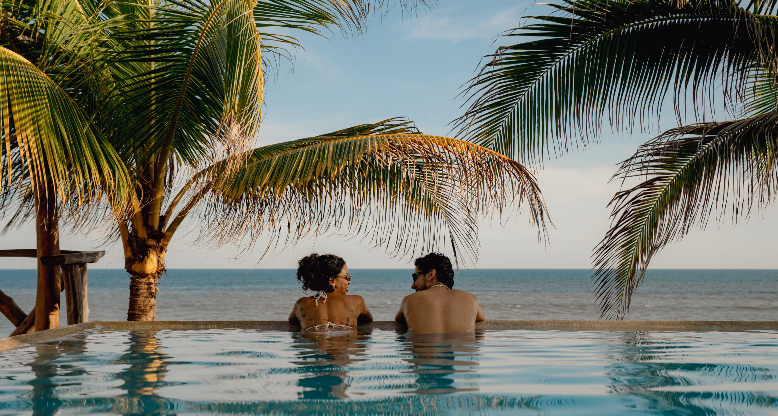 Two guests in the infinity pool at Puro Surf looking at the ocean in El Zonte