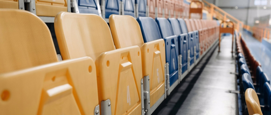 Rows of yellow, blue, and orange seats in an empty stadium or arena.
