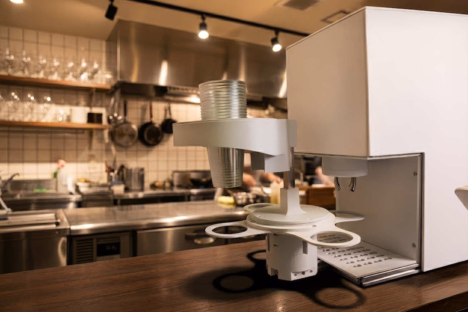Automated beverage dispensing system with stacked plastic cups in a kitchen setting.