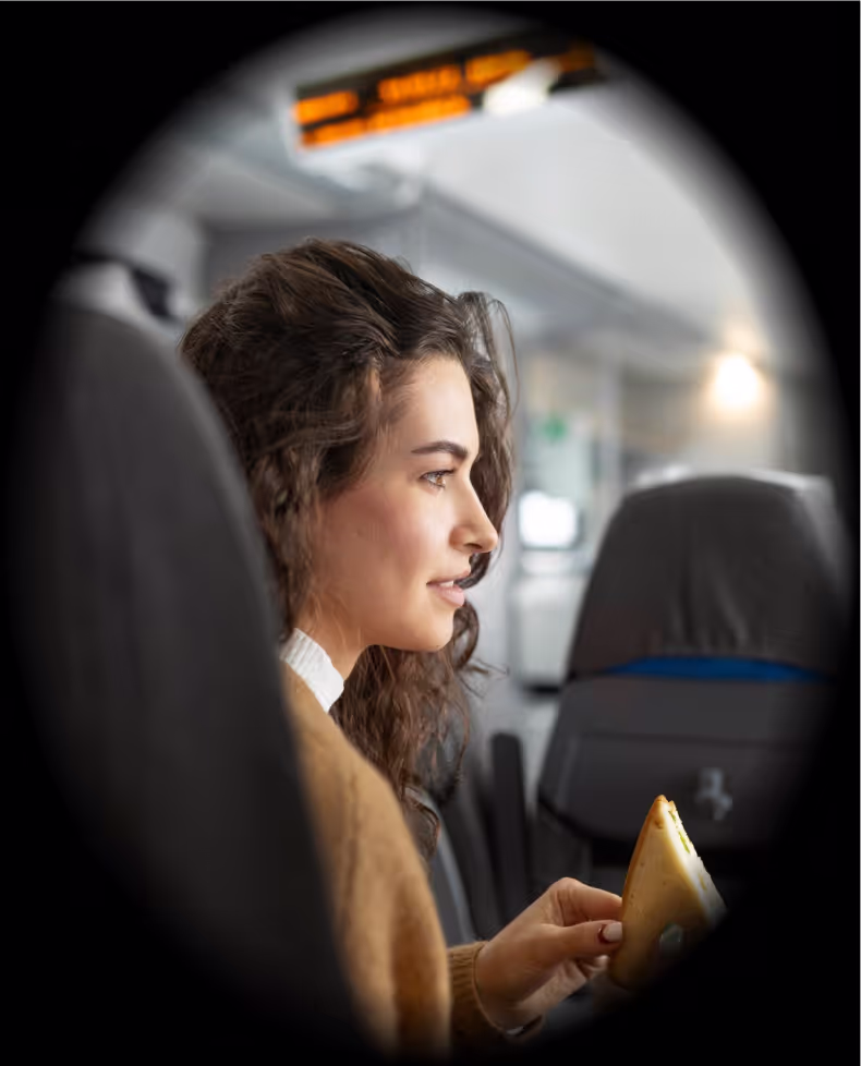 A woman in a brown sweater is holding a sandwich.