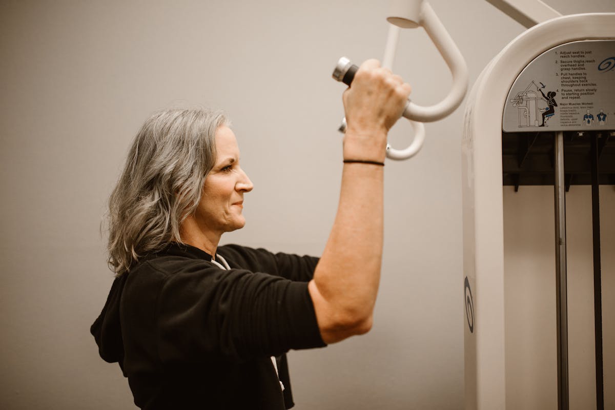 A confident mature woman in athletic wear in a fitness setting, communicating midlife strength and wellness