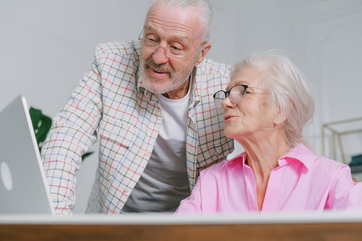 An elderly couple wearing eyeglasses talking together at home, communicating thoughtful family conversation about cognitive health