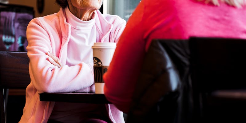 Senior mother and mature daughter sharing coffee in a cafe