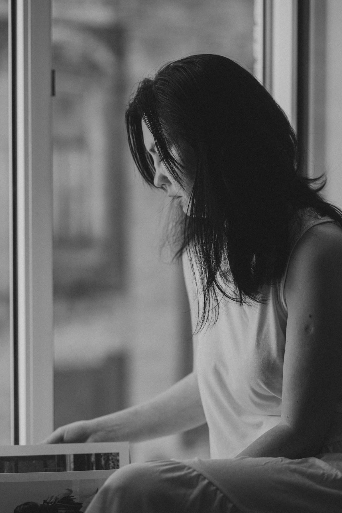 A contemplative woman sitting by a window in a quiet introspective moment