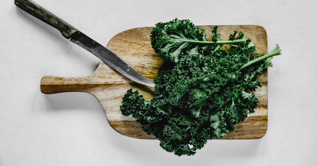 Close-up of fresh kale leaves on a wooden chopping board in a kitchen setting