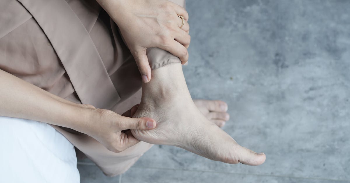 A person gently holding their ankle and foot, showcasing relaxation or foot care
