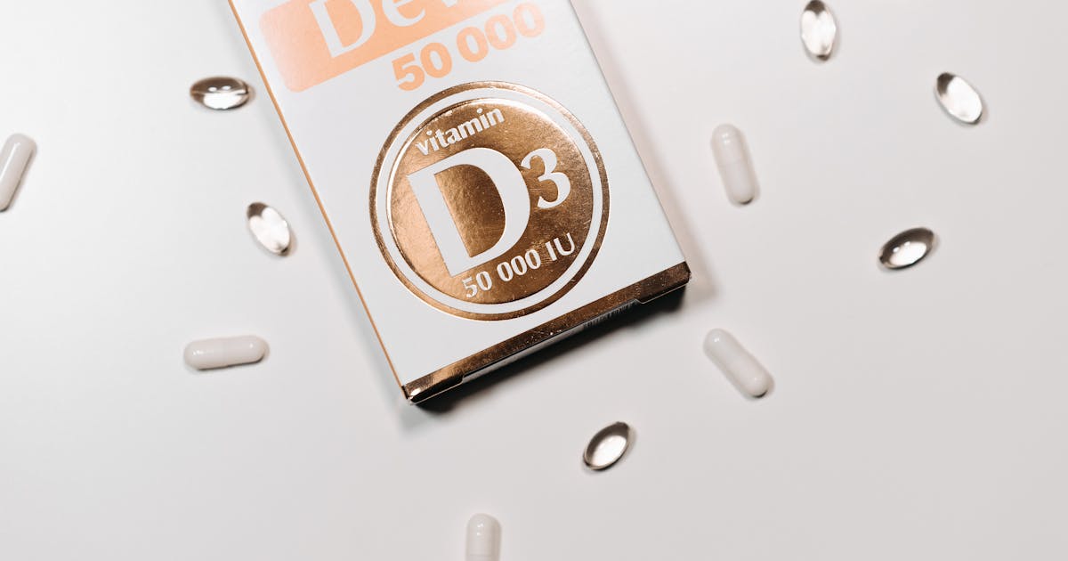 Flat lay of Vitamin D3 supplement box and capsules on a light background