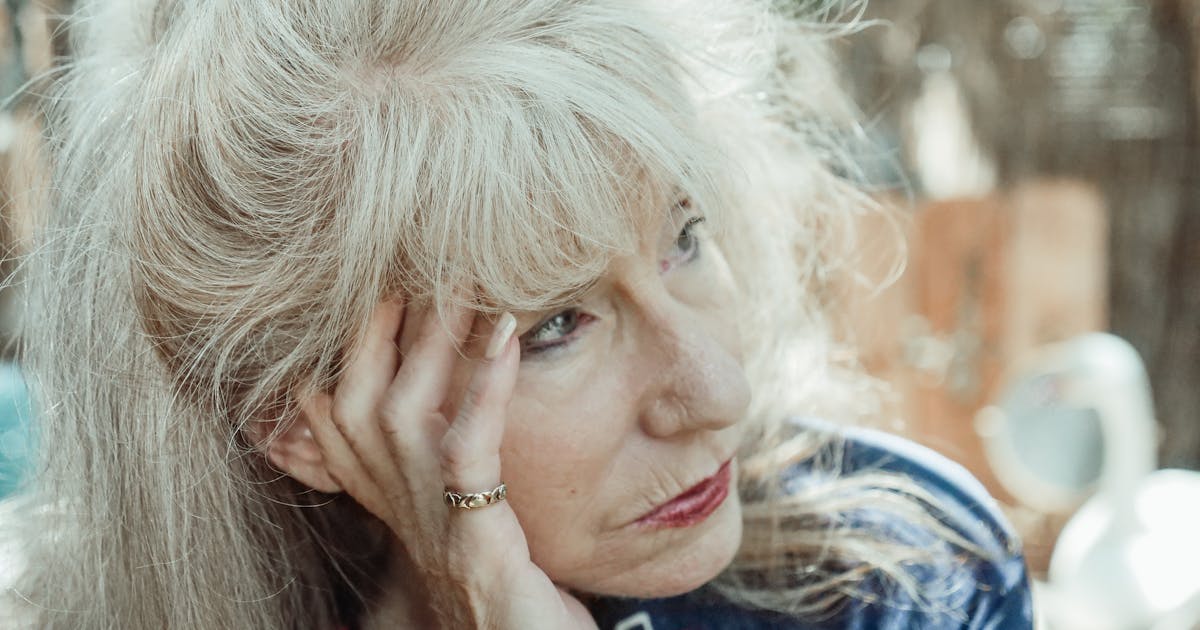 An introspective senior woman in thought, sitting outdoors on a sunny day