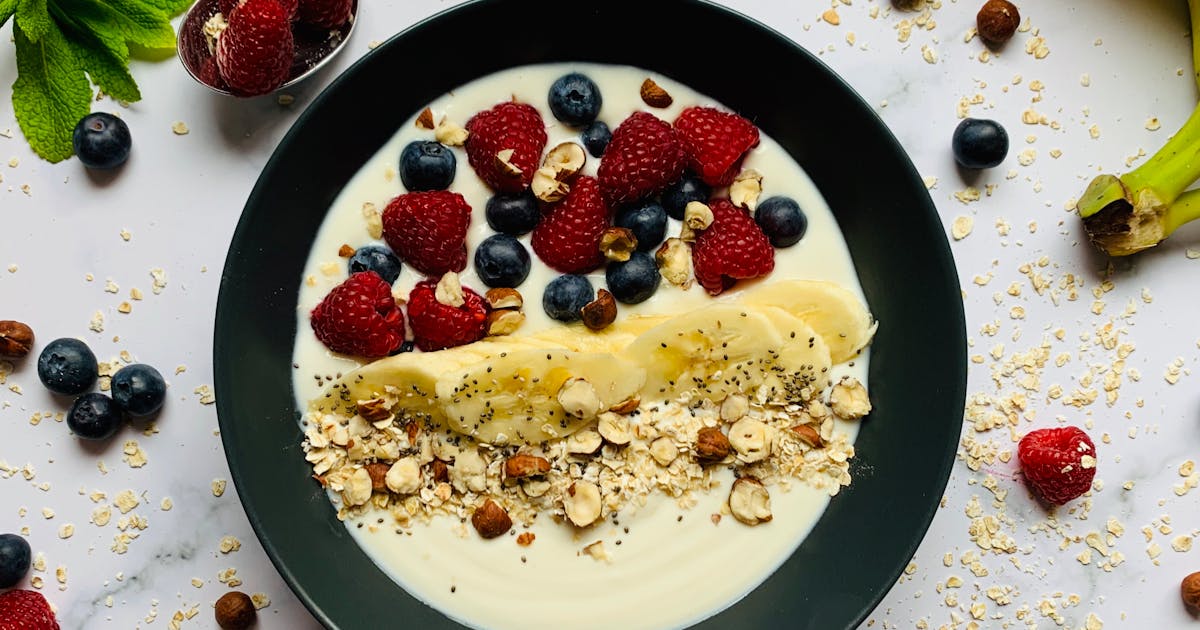 Top view bowl with delicious healthy yogurt with berries and bananas served with muesli and nuts