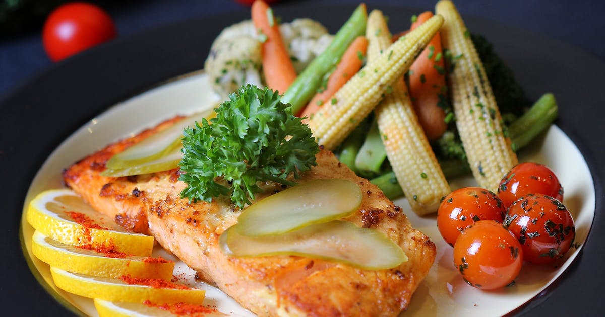 A beautifully plated salmon dish with fresh vegetables and lemon slices, perfect for a gourmet meal