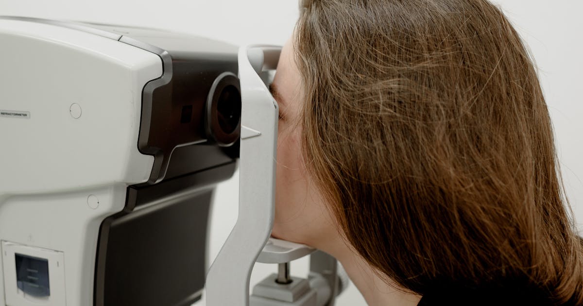 Side view of female client checking vision during medical treatment in ophthalmology clinic