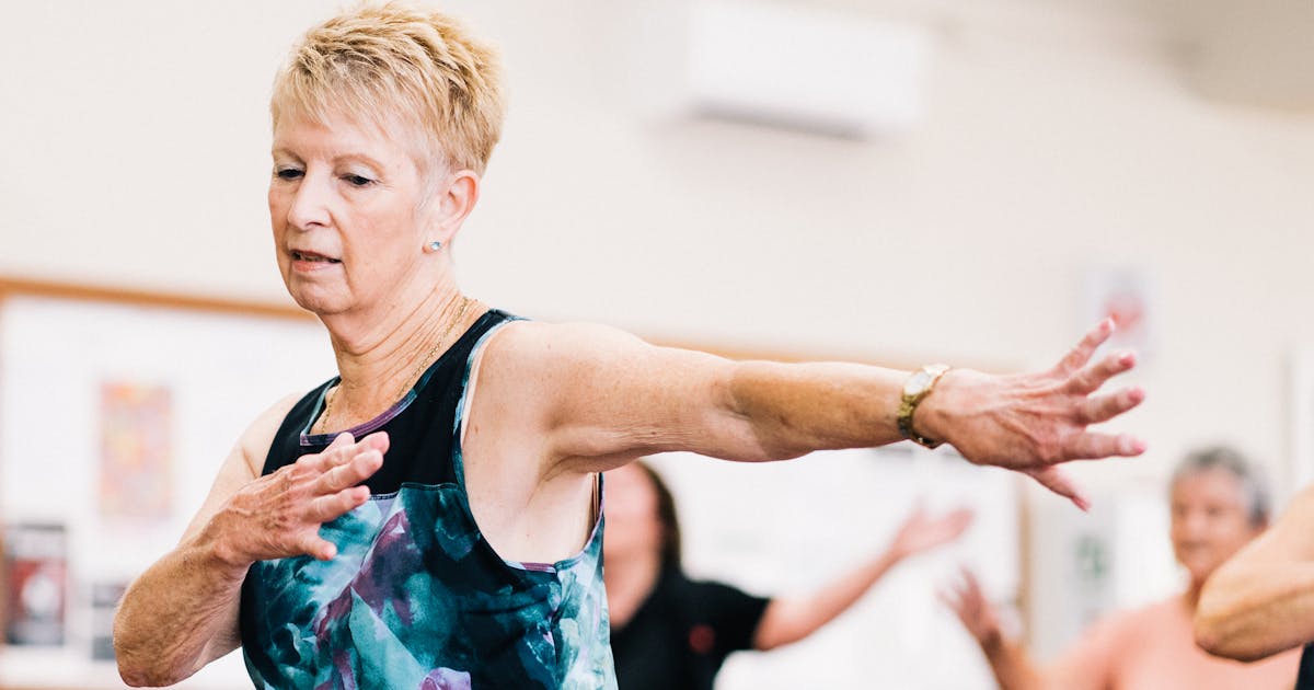 Senior woman participating in a lively fitness class indoors, embracing positive aging