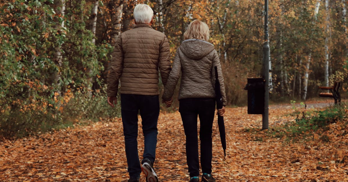 Senior couple enjoying a peaceful walk through a leafy park in Sweden