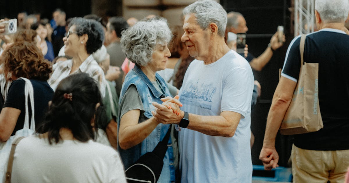 Senior couple dancing joyfully at an outdoor gathering, celebrating life and love