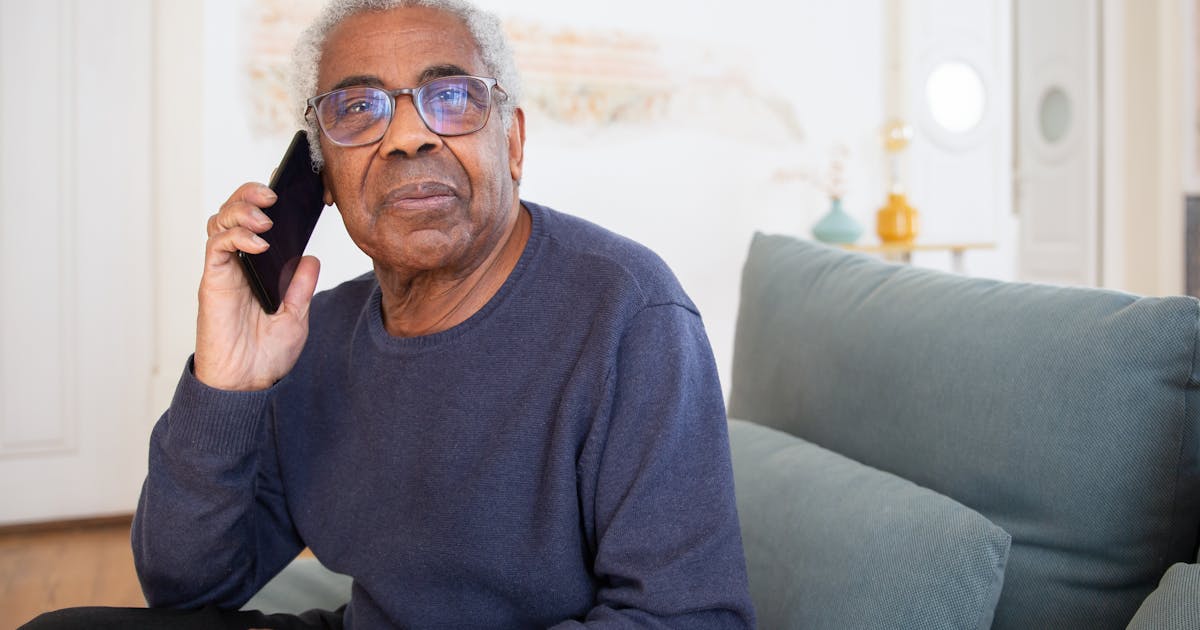 Senior man wearing glasses making a phone call while sitting on a sofa at home